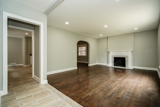 17344 Wisconsin St, Detroit, MI 48221 - unfurnished living room with arched walkways, wood finished floors, recessed lighting, a high end fireplace, and baseboards