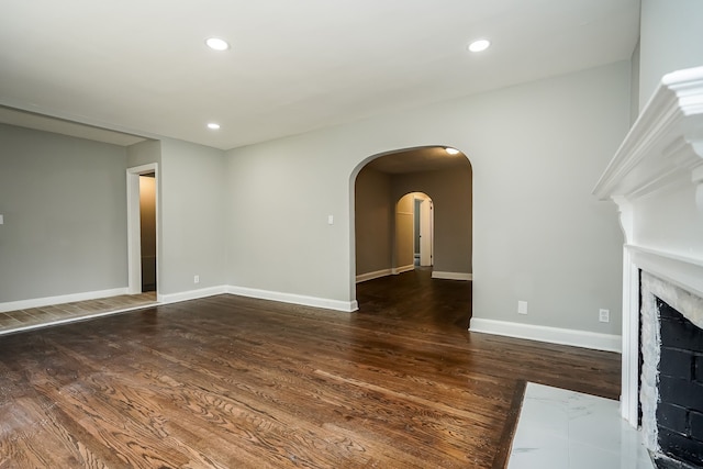 17344 Wisconsin St, Detroit, MI 48221 - unfurnished living room featuring wood finished floors, arched walkways, baseboards, recessed lighting, and a fireplace with flush hearth