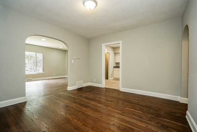 17344 Wisconsin St, Detroit, MI 48221 - spare room featuring arched walkways, dark wood-style flooring, and baseboards