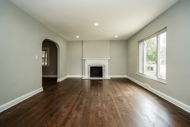 17344 Wisconsin St, Detroit, MI 48221 - unfurnished living room with dark wood-style floors, arched walkways, a fireplace with flush hearth, recessed lighting, and baseboards