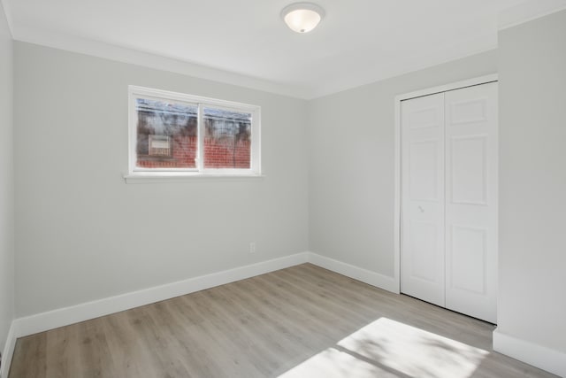 unfurnished bedroom featuring a closet, wood finished floors, and baseboards