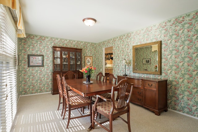 dining room with wallpapered walls, baseboards, and light colored carpet