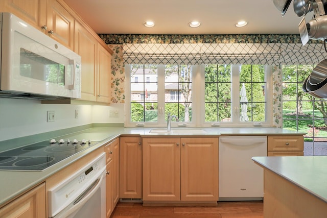 kitchen featuring white appliances, a sink, plenty of natural light, light countertops, and recessed lighting