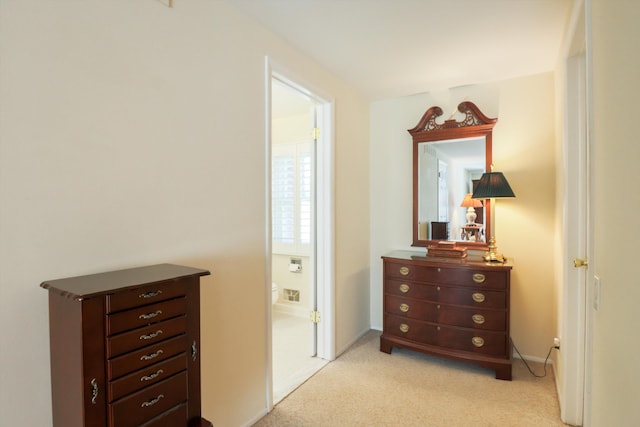 bedroom featuring light colored carpet, ensuite bathroom, and baseboards