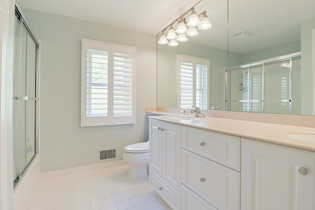full bathroom featuring a shower with shower door, plenty of natural light, double vanity, and toilet