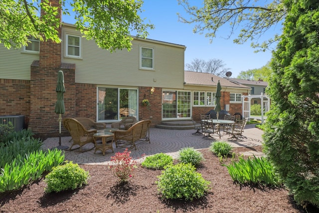 back of property with a patio area, brick siding, and central AC