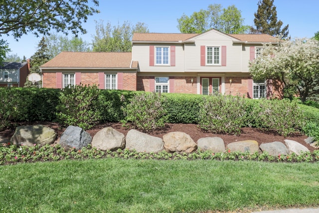 view of front facade with brick siding and a front yard