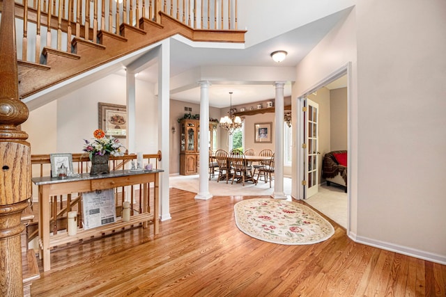 24391 Cavendish Ave E, Novi, MI 48375 - entryway featuring ornate columns, wood finished floors, a chandelier, baseboards, and a high ceiling