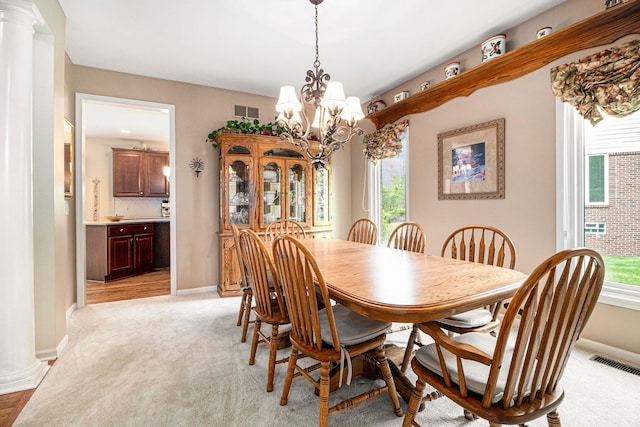 24391 Cavendish Ave E, Novi, MI 48375 - dining space featuring a chandelier, ornate columns, baseboards, and light carpet