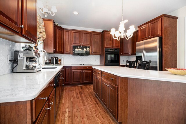 24391 Cavendish Ave E, Novi, MI 48375 - kitchen with black appliances, dark wood-style flooring, a chandelier, light countertops, and tasteful backsplash