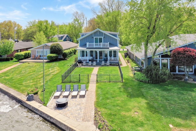 back of house with a balcony, board and batten siding, a patio area, a gate, and a fire pit