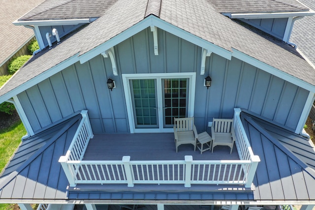 entrance to property with board and batten siding, roof with shingles, and a deck