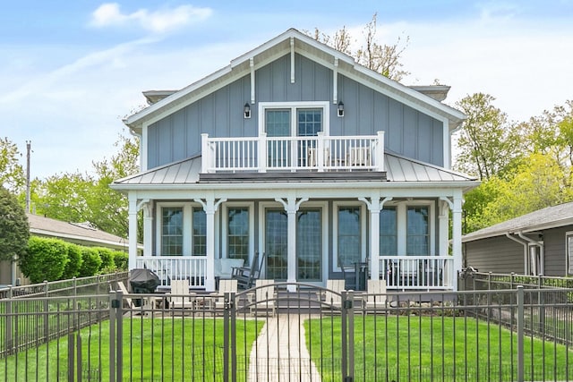 back of house featuring a balcony, a standing seam roof, covered porch, and board and batten siding