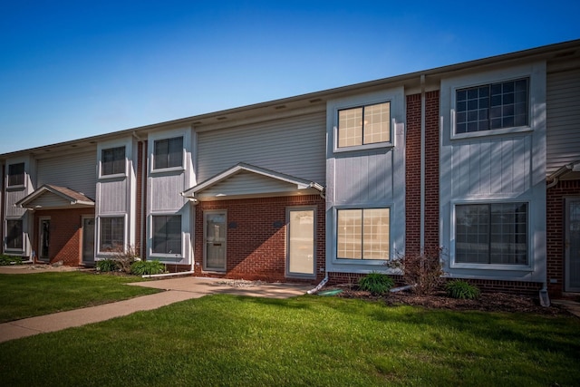 townhome / multi-family property with a front yard and brick siding