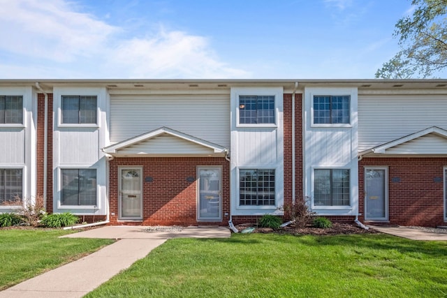 townhome / multi-family property featuring brick siding and a front yard