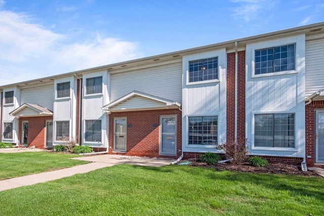 multi unit property featuring brick siding and a front yard