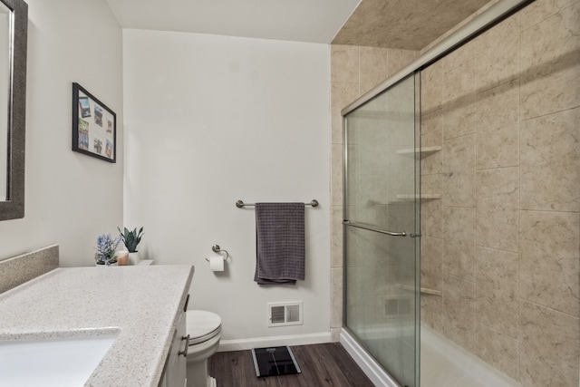 full bath featuring baseboards, a shower stall, vanity, wood finished floors, and toilet