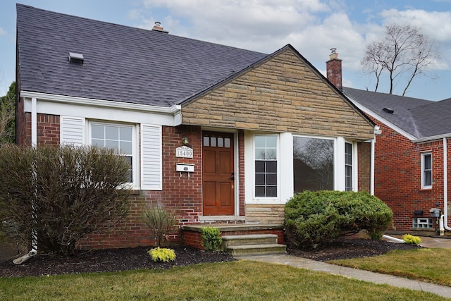 view of front of house featuring a chimney, brick siding, roof with shingles, and stone siding