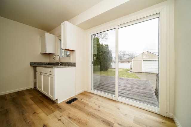 entryway featuring light wood-style floors, baseboards, and a sink