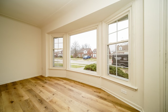 spare room featuring baseboards, plenty of natural light, and wood finished floors