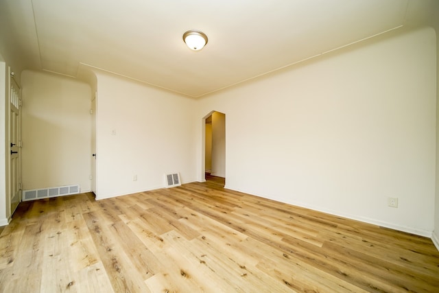unfurnished room featuring wood finished floors, arched walkways, and baseboards