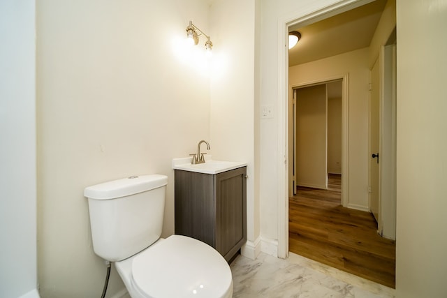 bathroom with toilet, vanity, and marble finish flooring