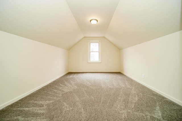 additional living space featuring carpet flooring, baseboards, and vaulted ceiling