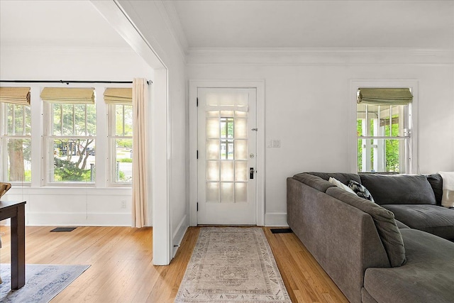doorway with crown molding, light wood finished floors, and baseboards