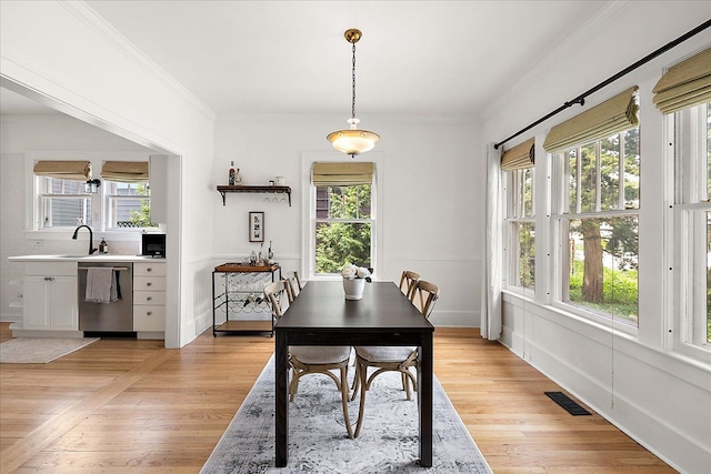 dining room featuring plenty of natural light, light wood finished floors, and ornamental molding