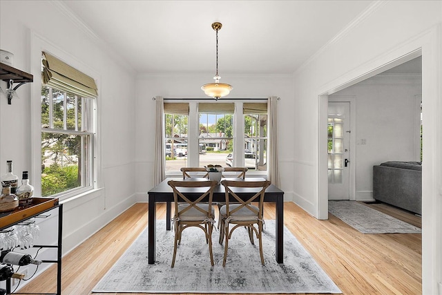 dining space with light wood finished floors, ornamental molding, and baseboards
