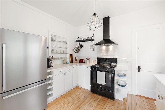 kitchen featuring open shelves, freestanding refrigerator, black range with gas stovetop, wall chimney exhaust hood, and light countertops