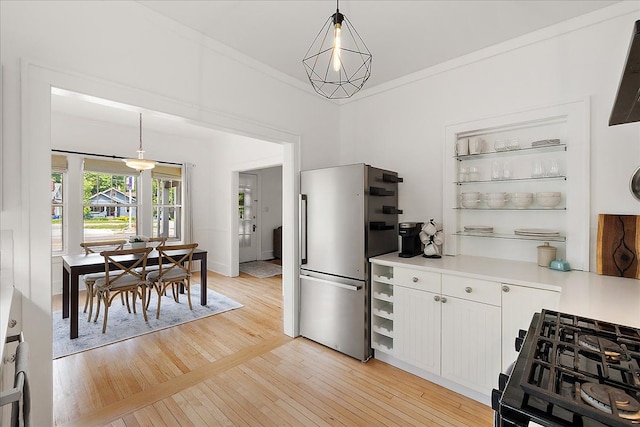 kitchen with freestanding refrigerator, light countertops, light wood-style floors, pendant lighting, and white cabinets