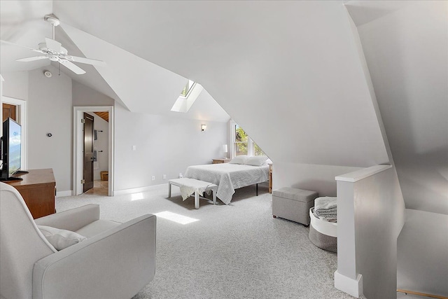 carpeted bedroom with vaulted ceiling, a skylight, baseboards, and a ceiling fan