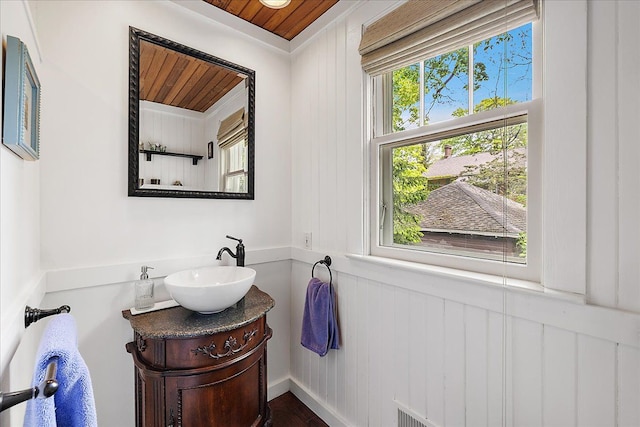 bathroom featuring wooden ceiling, vanity, wooden walls, and wood finished floors