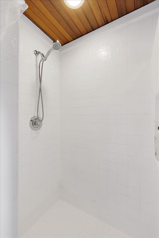 bathroom with a tile shower and wood ceiling
