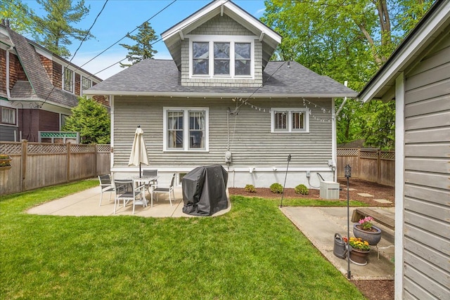 back of property with roof with shingles and a patio