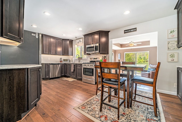 9703 Tower Rd, South Lyon, MI 48178 - kitchen with appliances with stainless steel finishes, a ceiling fan, dark brown cabinets, dark wood-style flooring, and recessed lighting