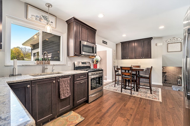 9703 Tower Rd, South Lyon, MI 48178 - kitchen with appliances with stainless steel finishes, a sink, dark wood-type flooring, dark brown cabinetry, and light stone counters