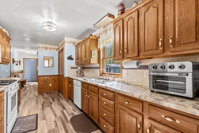 8869 E Hawley Rd, Hesperia, MI 49421 - kitchen with a sink, white appliances, light countertops, light wood-style floors, and a wainscoted wall