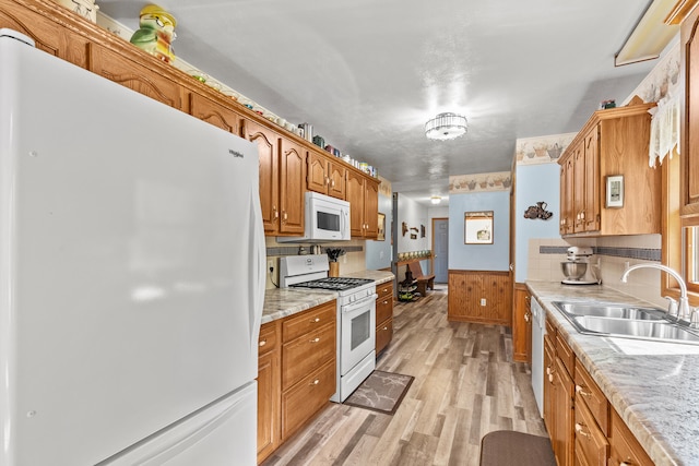 8869 E Hawley Rd, Hesperia, MI 49421 - kitchen with white appliances, a sink, light wood finished floors, brown cabinets, and wainscoting