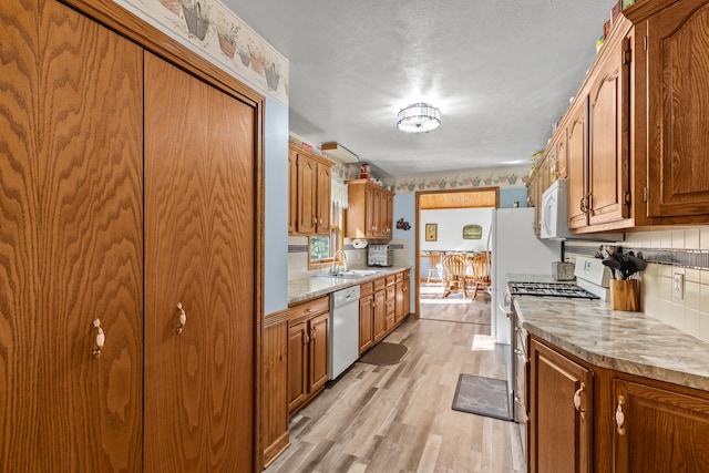 8869 E Hawley Rd, Hesperia, MI 49421 - kitchen featuring white appliances, a sink, light wood-style floors, and brown cabinets