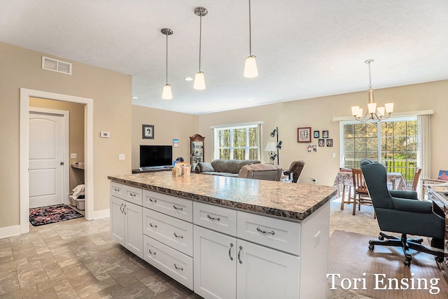 1026 Grosvenor Dr Unit 27, Greenville, MI 48838 - kitchen with a chandelier, white cabinets, open floor plan, a center island, and decorative light fixtures