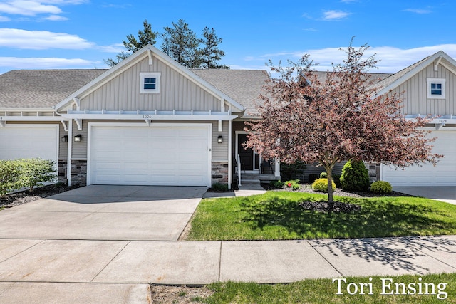 1026 Grosvenor Dr Unit 27, Greenville, MI 48838 - craftsman-style house featuring board and batten siding, stone siding, concrete driveway, a front yard, and an attached garage