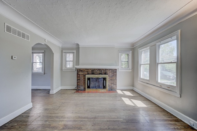 18613 Santa Rosa Dr, Detroit, MI 48221 - unfurnished living room with arched walkways, a textured ceiling, plenty of natural light, wood finished floors, and baseboards