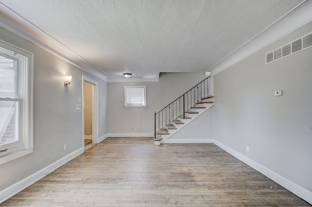 18613 Santa Rosa Dr, Detroit, MI 48221 - unfurnished living room featuring a textured ceiling, stairs, wood finished floors, and baseboards