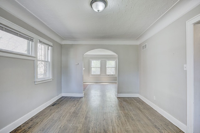 18613 Santa Rosa Dr, Detroit, MI 48221 - empty room with arched walkways, wood finished floors, baseboards, and a textured ceiling