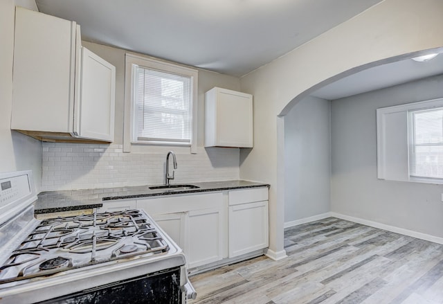 18613 Santa Rosa Dr, Detroit, MI 48221 - kitchen featuring a sink, white gas range, arched walkways, decorative backsplash, and white cabinetry