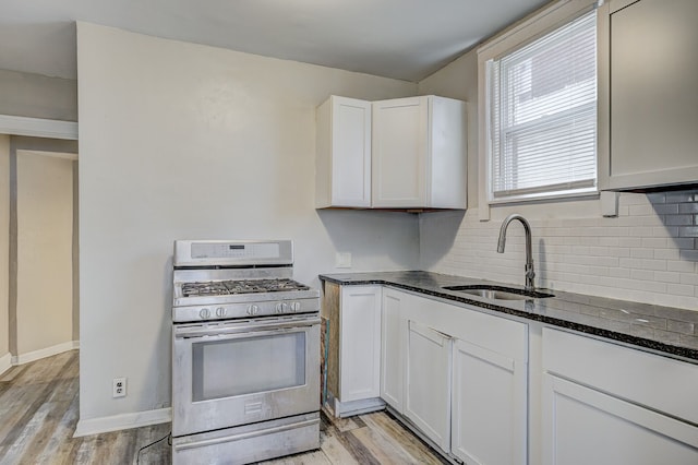 18613 Santa Rosa Dr, Detroit, MI 48221 - kitchen with stainless steel gas stove, a sink, dark stone counters, backsplash, and light wood finished floors