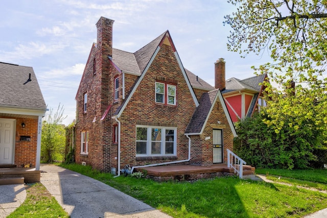18644 Santa Rosa Dr, Detroit, MI 48221 - tudor-style house featuring a chimney, a front lawn, brick siding, and roof with shingles