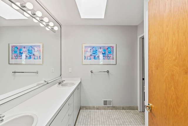 full bathroom featuring a skylight, tile patterned flooring, double vanity, and baseboards